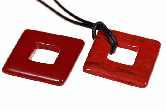 Dvi raudonos spalvos kvadratinės pakabos su viduriniu skydeliu, viena su juoda virvele ant balto fono.