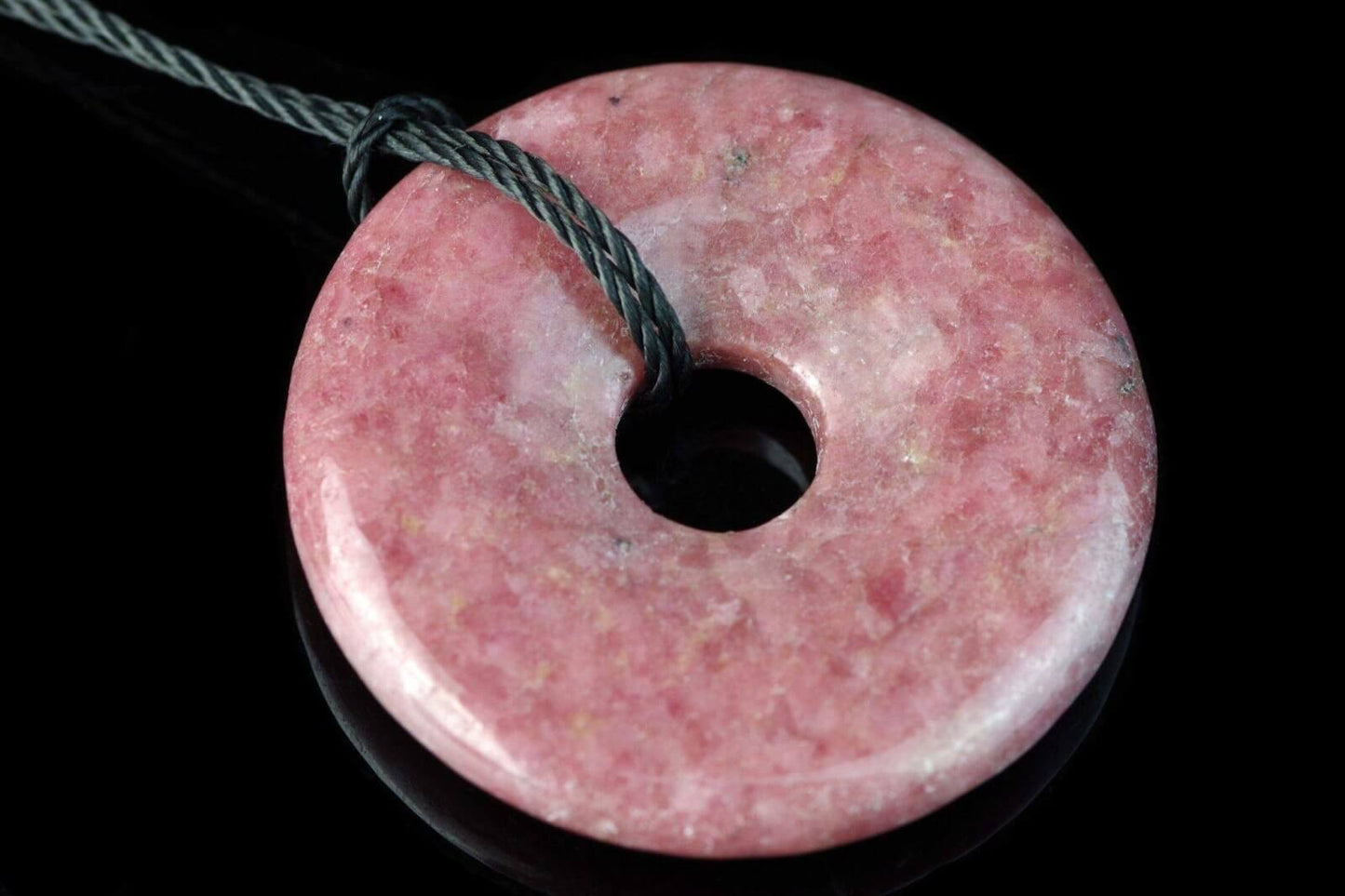 Rodonitas pakabukas – Diskas 30mm, natūralus rausvas kristalas, gludintas ir sklandžiai apvalintas su skyle viduryje, tvirtai pritvirtintas prie juodos virvelės.