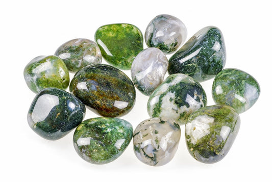 Keliolika poliruotų, apvalių akmenų su žalia ir balta dailine raštu ant baltos fono.