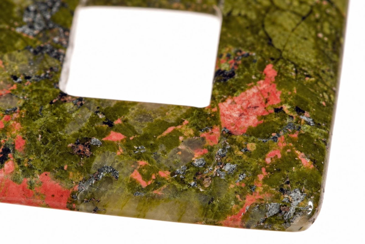 Pakabukas iš unakito su žalia, raudona ir juoda spalvų raštu bei baltu kvadratu viršuje ant balto fono.
