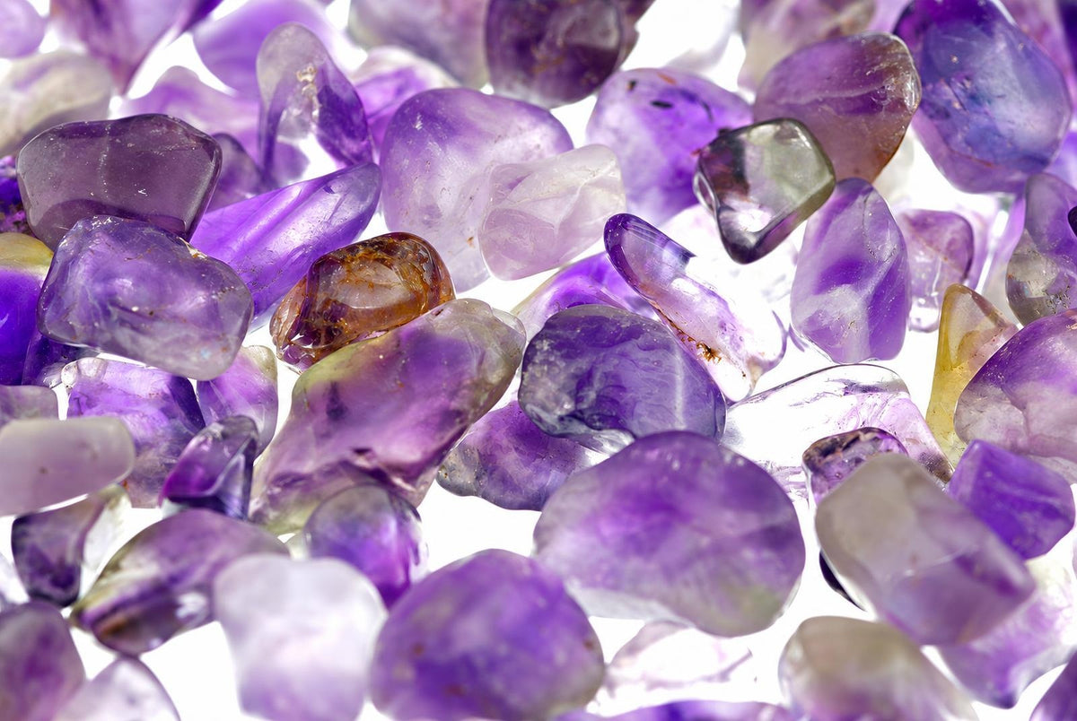 Krautuvėse išdėstyti ametišto akmenų gabaliukai su violetinėmis, baltomis ir raudonai oranžinėmis spalvomis.
