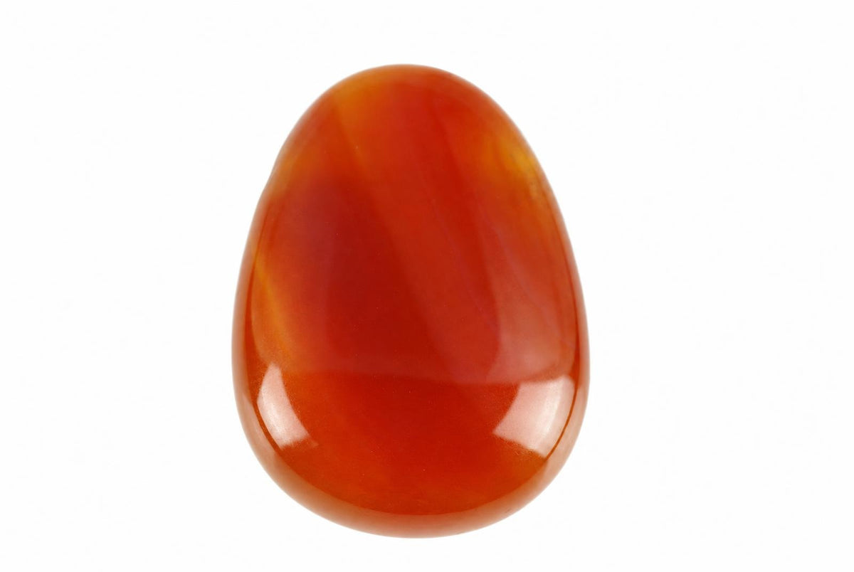 Raudona, blizganti karneolio formos akmuo ant balto fono.