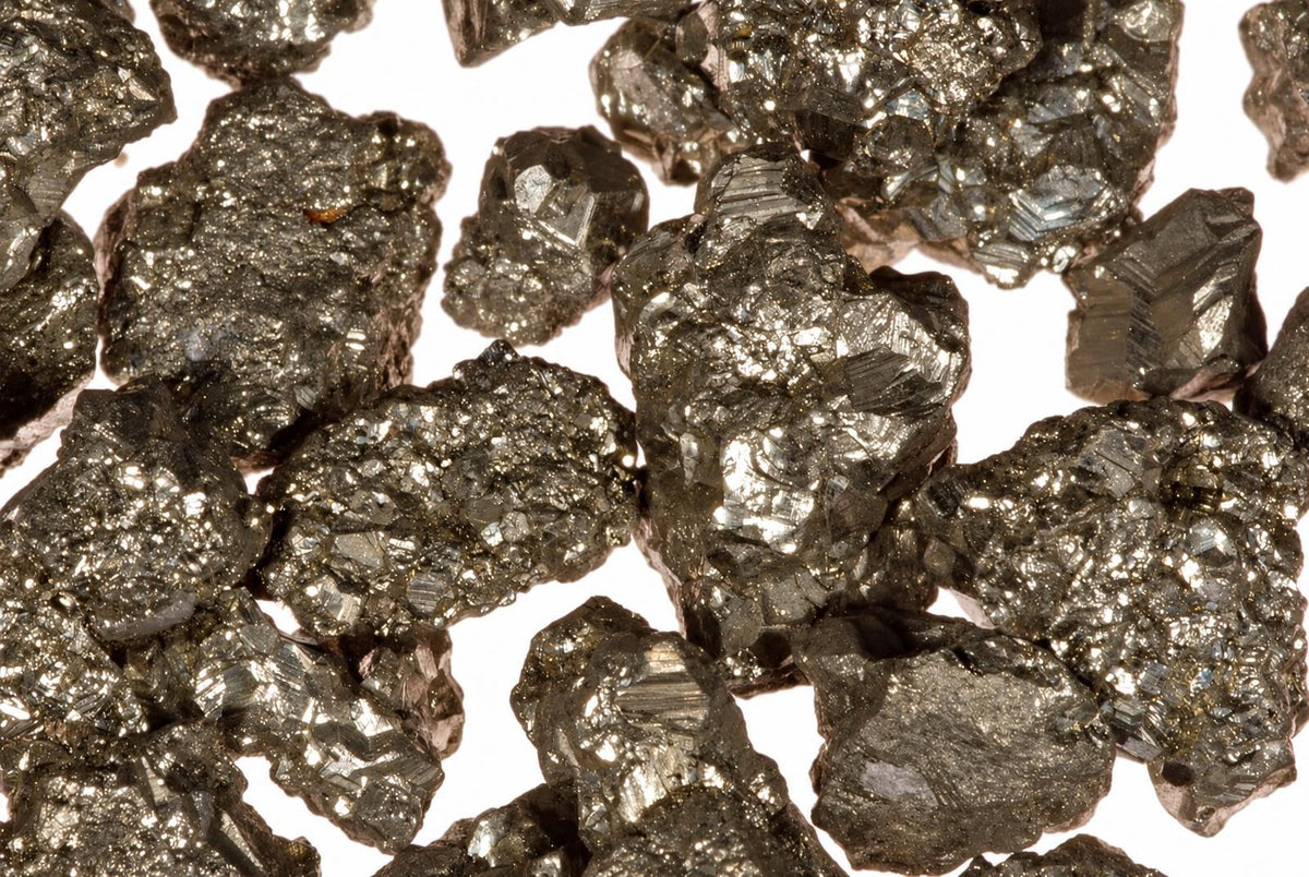Kelių piritų kristalai su blizgančia, metaline paviršiaus tekstūra ir tamsiai pilkomis spalvomis ant baltos fono.