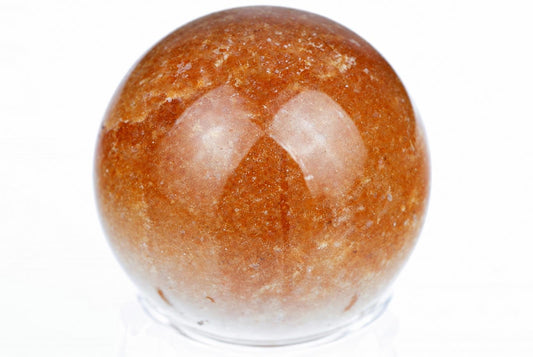 Poliruota raudona sfera su blyksinčiais atspindžiais ant balto fono.