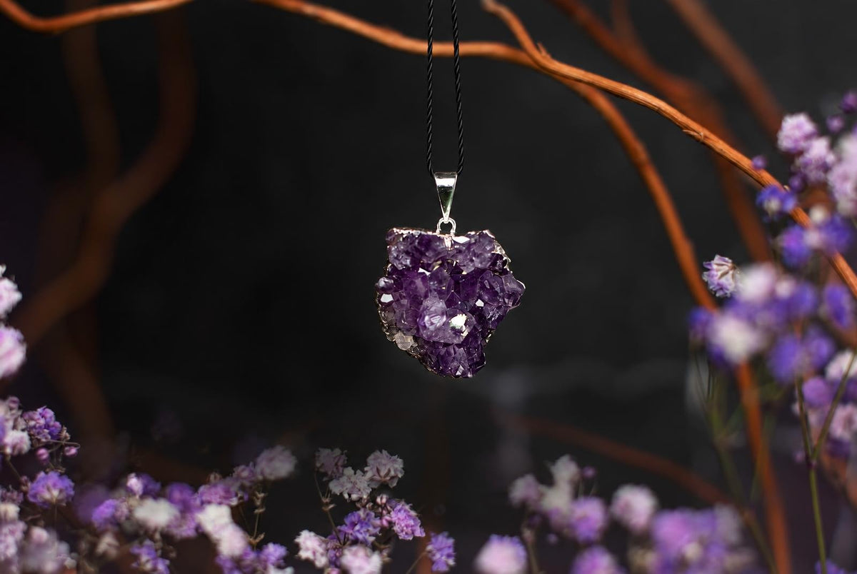 Pakabukas su violetna, kristalinu akmenuku ir sidabrine kabine ant juodos siunelės.